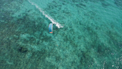 Aerial overhead shot showing kite surfer surfing on clear Pacific Ocean during beautiful weather...