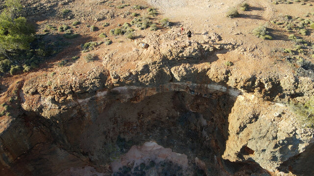 Young Female Traveller Stand Front To Spectacular Cliff Precipice At Sunrise Falling Over Charles Knife Canyon Exmouth, Western Australia, Aerial Drone Shot