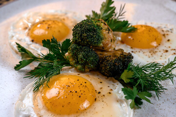 Fried eggs with fried broccoli and herbs