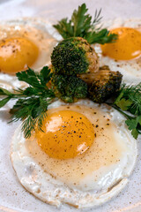 Fried eggs with fried broccoli and herbs