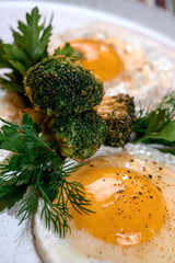 Fried eggs with fried broccoli and herbs