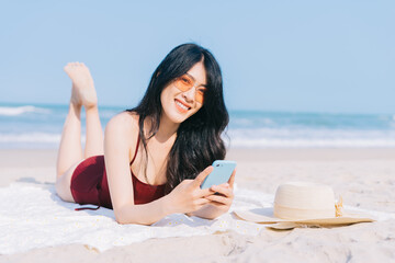 Beautiful young asian woman in swimwear relaxing at the beach during summer vacation