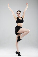 Full length portrait of a young fitness woman in sportswear posing and jumping isolated over gray background