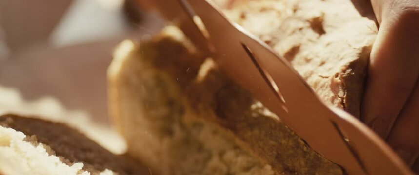 Knife cuts fresh hot baked bread female hand close up