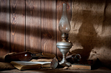 A vintage kerosene lamp covered in dust and soot, shot against a background of wood panels and...