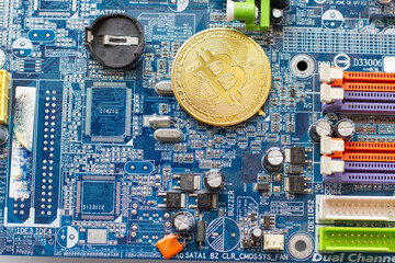 Bitcoin coins on computer circuit board chip. Golden coin with bitcoin symbol on a motherboard