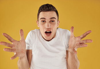 happy brunette man on yellow background shows positive hand gesture