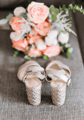 Bridal bouquet of pink, white roses and greenery , gray women shoes  on bed.