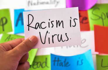 Word card 'Racism is virus.' holding in hand, concept for calling all people around the world to stop hating, hurting and harassing Asian people in the spreading of Covid-19 crisis. 