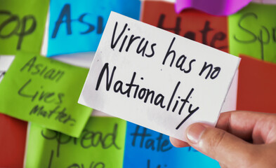 Word card 'Virus has no nationality.' holding in hand, concept for calling all people around the world to stop hating, hurting and harassing Asian people in the spreading of Covid-19 crisis. 