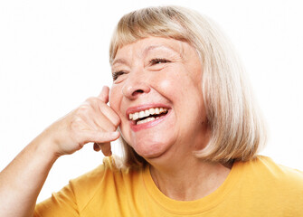 senior woman wearing yellow shirt standing over white background smiling doing phone gesture