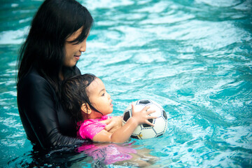 mother carrying her baby in the swimming pool