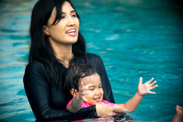 mother carrying her baby in the swimming pool
