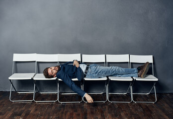 A man lies on chairs waiting for an interview job manager professional