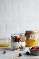 Granola with yogurt and fresh berries in a transparent glass. Image with copy space, vertical orientation, side view.