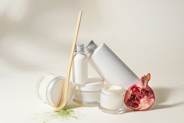 Composition with natural cosmetic products and pomegranate on white background