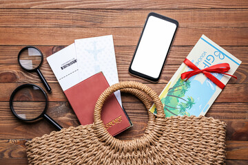 Travel gift voucher, mobile phone and passport with tickets on wooden background