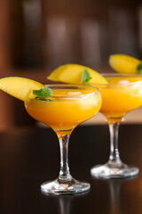 Glasses of tasty mango margarita on table in bar