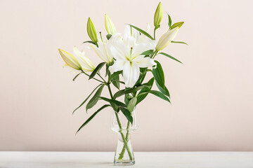 Vase with beautiful lily flowers on table against light background
