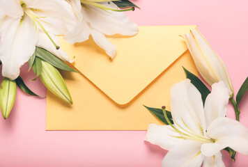 Beautiful lily flowers and envelope on color background