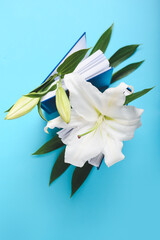 Naklejka premium Books with beautiful lily flowers on color background