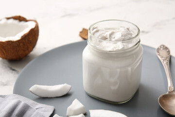 Jar with coconut cream on light background, closeup
