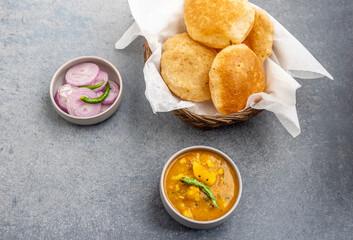 Masala Aloo Sabzi or Indian potato gravy served with fried puri or Poori with sliced onion and green chilly 