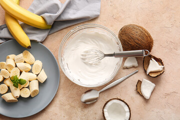 Bowl with coconut cream and whisk on color background
