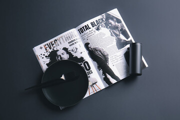 Plate, cutlery and magazine on dark background