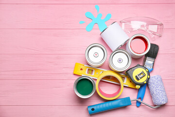 Fototapeta na wymiar Cans of paints and tools on color wooden background