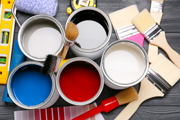 Cans of paints and tools on dark wooden background