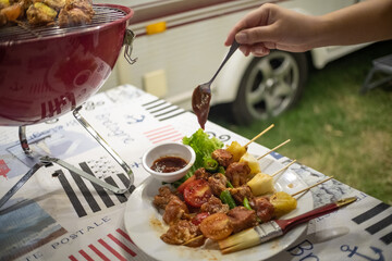 Friends making barbecue BBQ grilling over a hot fire  in the nature.Dinner party