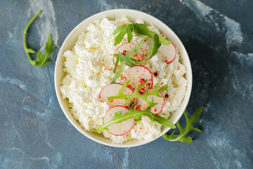 Bowl with cottage cheese on color background