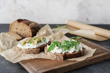 Tasty sandwiches with cottage cheese and olives on table