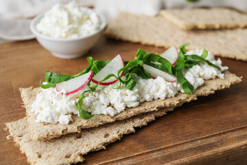Crispbreads with cottage cheese and radish on wooden background