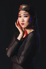 Portrait of stylish Asian woman with painted face on dark background