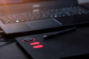Close-up of a laptop with a graphics tablet on a black table. Designer workplace, freelance worker