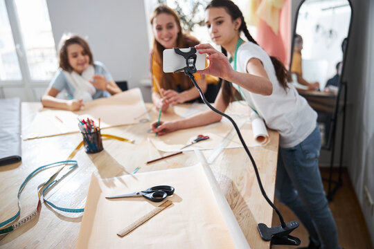 Adorable girls recording sewing vlog in workshop