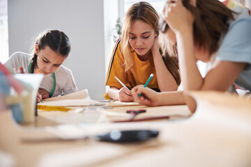 Adorable children making sewing patterns in tailor atelier