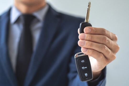 Businessman agent holding car keys offering new car salesman Automobile Vehicles Concept