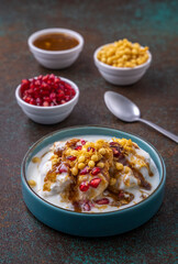 Indian tasty street food Dahi Bhalla or  Dahi Vada garnished with tamarind sauce and pomegranate seeds 