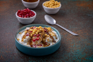 Indian tasty street food Dahi Bhalla or  Dahi Vada garnished with tamarind sauce and pomegranate seeds 