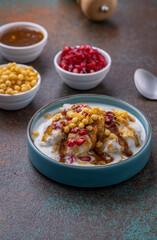 Indian tasty street food Dahi Bhalla or  Dahi Vada garnished with tamarind sauce and pomegranate seeds 