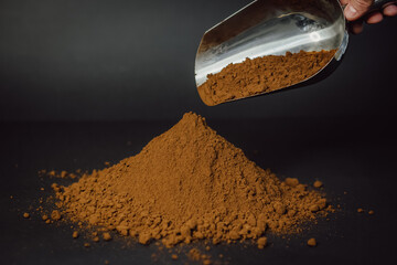 Finely ground coffee drips out of the scoop. Coffee powder background.