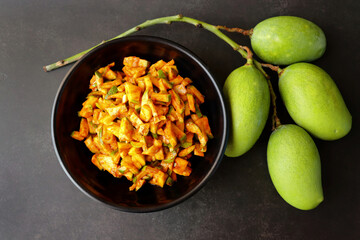 Green mango salad. Raw mango instant pickle. also known as kairichi koshimbir in Marathi. copy space over black background. Chopped raw green mangos mixed with salt, red chilli powder and sugar. 