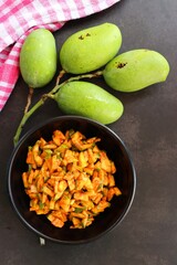 Green mango salad. Raw mango instant pickle. also known as kairichi koshimbir in Marathi. copy space over black background. Chopped raw green mangos mixed with salt, red chilli powder and sugar. 