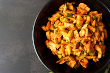 Green mango salad. Raw mango instant pickle. also known as kairichi koshimbir in Marathi. copy space over black background. Chopped raw green mangos mixed with salt, red chilli powder and sugar. 