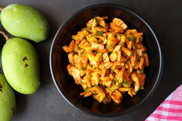 Green mango salad. Raw mango instant pickle. also known as kairichi koshimbir in Marathi. copy space over black background. Chopped raw green mangos mixed with salt, red chilli powder and sugar. 