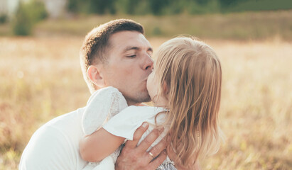 
dad kissing daughter in the park