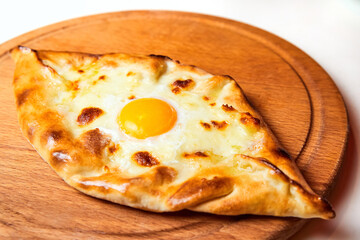 Ajarian traditional flatbread khachapuri or hachapuri with cheese, egg and butter on a plate.